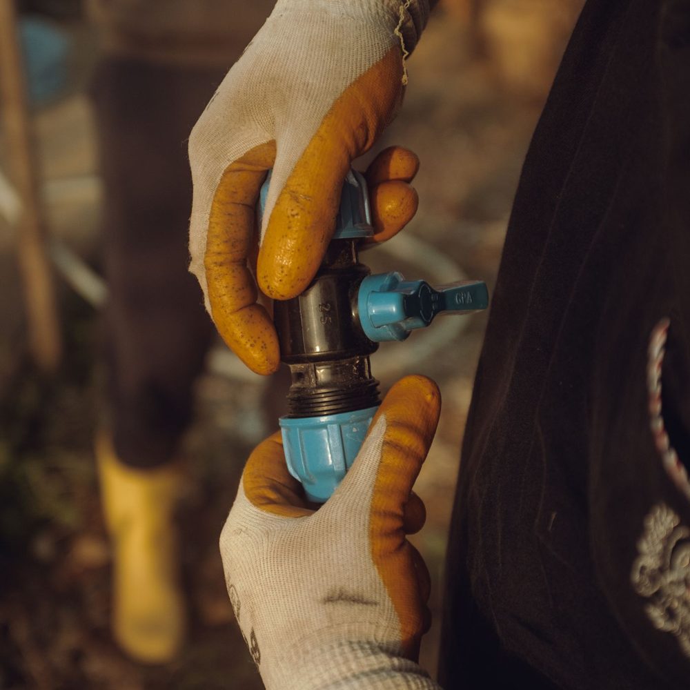 Gloved hands tightening a compression fitting on a supply line